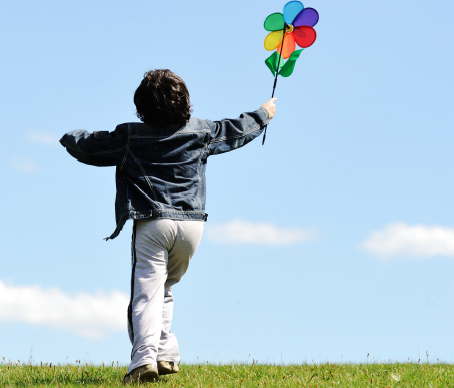 Niño corriendo con un molinillo de viento.